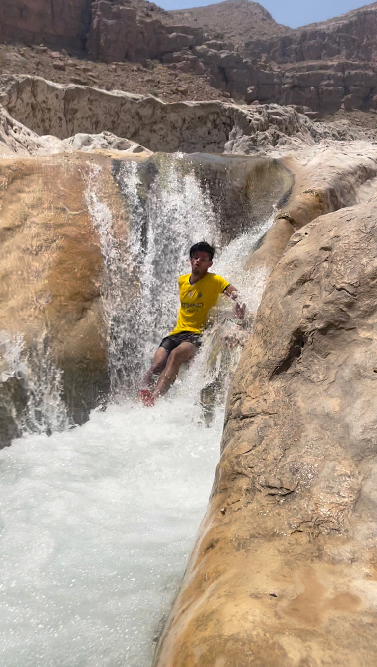 picture of Amjad in the middle of going down a waterfall slide